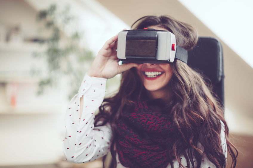 Young woman is using head-mounted virtual reality goggles